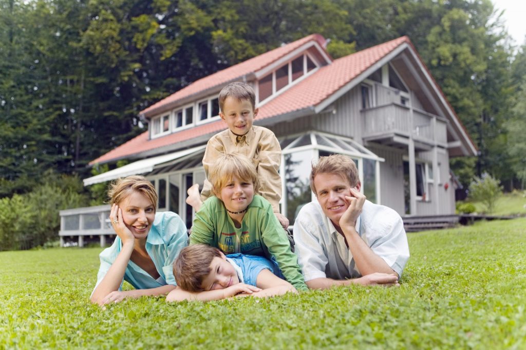 Familie vor ihrem Ferienhaus - Versicherungsschutz bei Vermietung
