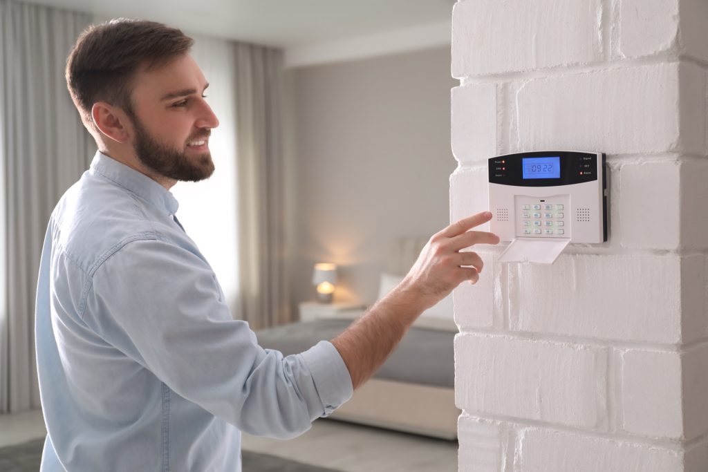 Mann gibt Code an Alarmanlage ein - Einbruchschutz fuer das Ferienhaus