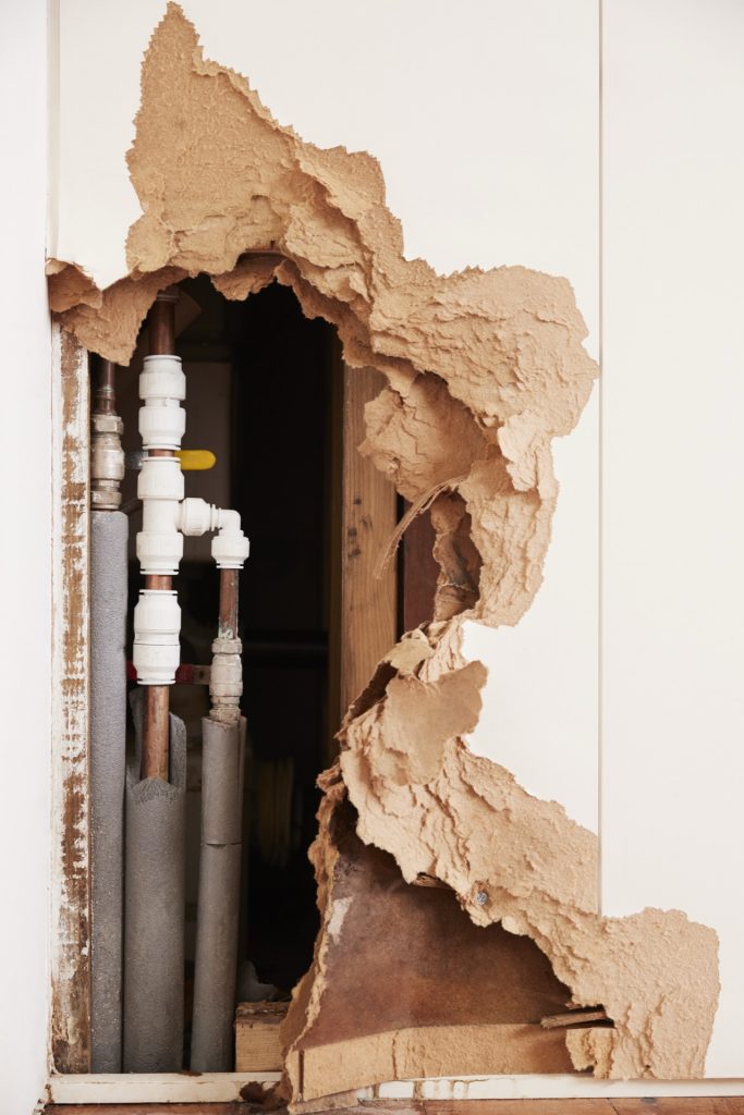 Beschaedigte Wand mit Wasserrohren - Legionellen-Praevention im Ferienhaus-Wassersystem